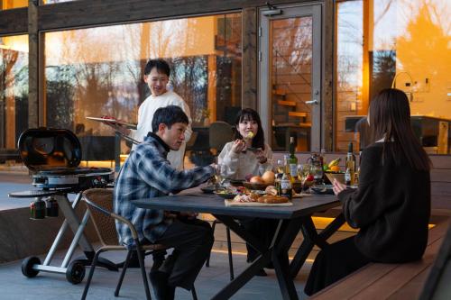 a group of people sitting around a table eating food at Villa Metsä KARUIZAWA ヴィラメッサ軽井沢 in Karuizawa