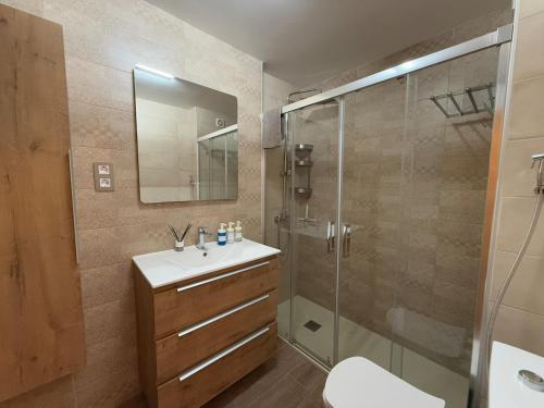 a bathroom with a sink and a glass shower at Modern & sunny beach apartment in Fuengirola