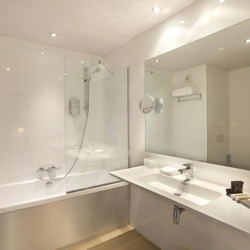 a bathroom with a shower and a sink and a mirror at Hôtel de Paris in Besançon