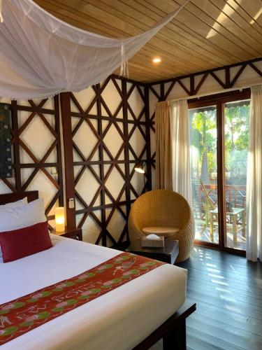a bedroom with a bed and a chair in a room at ViewPoint Ecolodge in Nyaung Shwe
