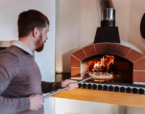a man holding a spatula in a brick oven at Yzerfontein Villa Fantastica - No Loadshedding in Yzerfontein