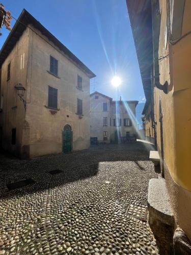 a cobblestone street with two buildings and the sun at Campidoglio vacation home in Lenno
