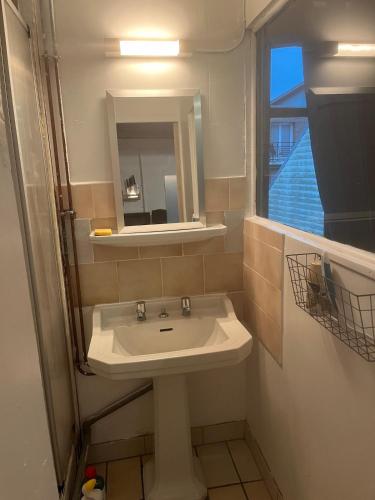 une salle de bain avec un lavabo, un miroir et une fenêtre dans l'établissement Studio le petit Bouclet, au Tréport