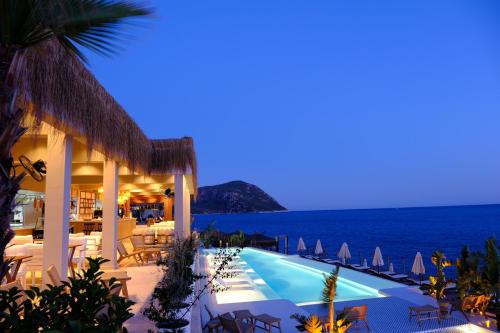 a resort with a pool and the ocean at night at Lures Hotel in Kalkan