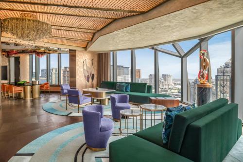 a lobby with green chairs and tables and windows at W Macau - Studio City in Macau