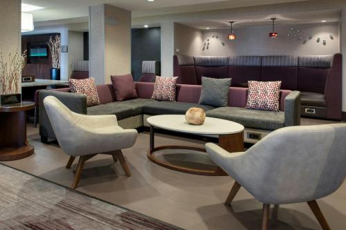a waiting room with couches and a table and chairs at Courtyard Newburgh Stewart Airport in Newburgh