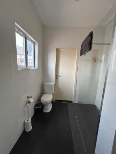 a white bathroom with a toilet and a window at Three bedroom luxurious house "Owusu- ansah transformer" in Pantang