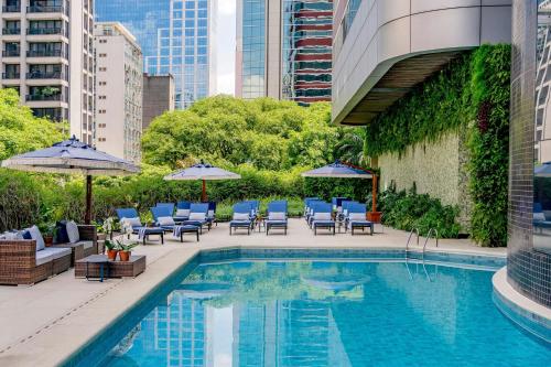 a swimming pool with chairs and umbrellas next to a building at Renaissance São Paulo Hotel in Sao Paulo
