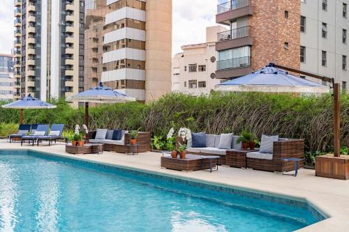 a pool with chairs and umbrellas next to a building at Renaissance São Paulo Hotel in Sao Paulo