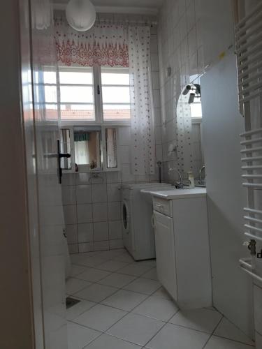 a bathroom with a sink and a washing machine at Apartman Veiger4 in Siófok
