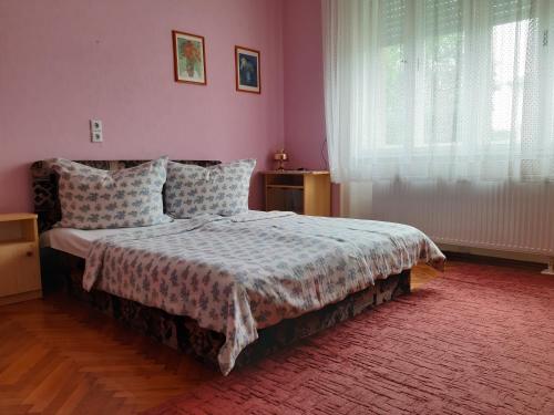a bedroom with a bed and a pink wall at Apartman Veiger4 in Siófok