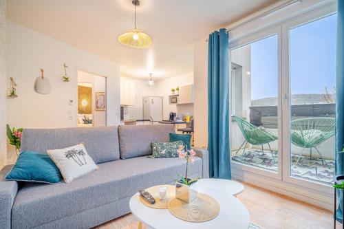 un salon avec un canapé et une grande fenêtre dans l'établissement Tropical nest - Taverny - Ligne H, à Taverny