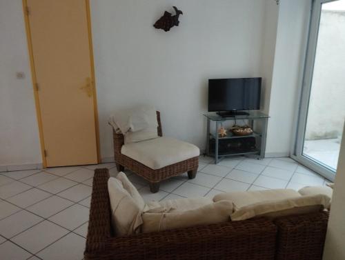 - un salon avec un canapé, une chaise et une télévision dans l'établissement T2 atypique côté Brassens, à Sète