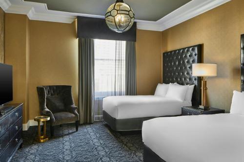 a hotel room with a bed and a chair at Le Pavillon, New Orleans, a Tribute Portfolio Hotel in New Orleans