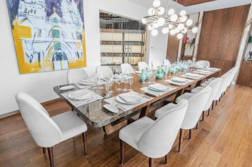 a long dining room table with white chairs and a painting at Sheraton Quito in Quito