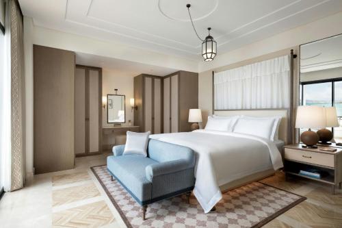 a bedroom with a large bed and a blue chair at The St. Regis La Bahia Blanca Resort - Tamuda Bay in Fnidek