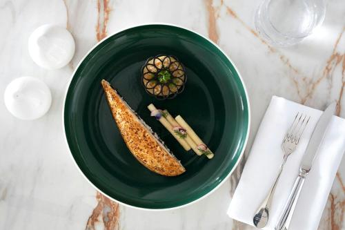 a green plate with a banana on a table at The St. Regis La Bahia Blanca Resort - Tamuda Bay in Fnidek