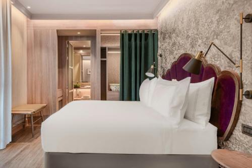 a bedroom with a large white bed and a bathroom at Querencia de Sevilla, Autograph Collection in Seville