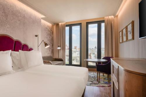 a hotel room with a bed and a desk and a room at Querencia de Sevilla, Autograph Collection in Seville
