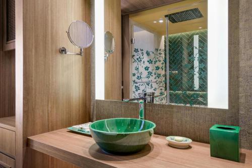 a bathroom with a green sink and a mirror at Querencia de Sevilla, Autograph Collection in Seville
