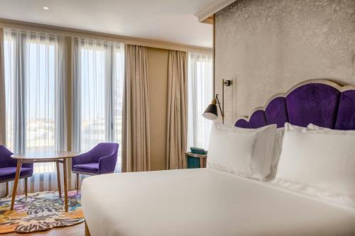 a hotel room with a bed and purple chairs at Querencia de Sevilla, Autograph Collection in Seville
