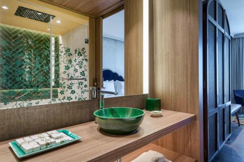 a bathroom with a green bowl sink on a wooden counter at Querencia de Sevilla, Autograph Collection in Seville