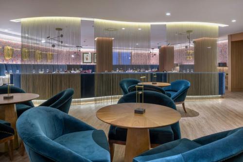 a waiting room with blue chairs and tables at Querencia de Sevilla, Autograph Collection in Seville