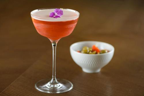a drink in a glass next to a bowl of vegetables at Querencia de Sevilla, Autograph Collection in Seville