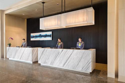 three men standing at a reception desk in a lobby at Courtyard by Marriott Iloilo in Iloilo City