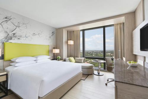 a hotel room with a white bed and a tv at Courtyard by Marriott Iloilo in Iloilo City