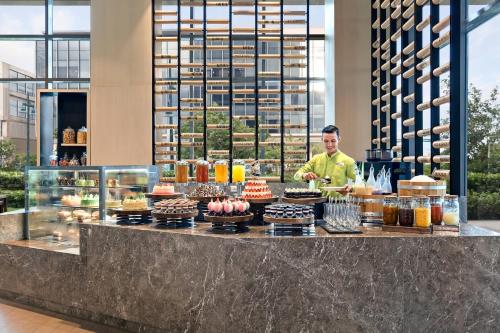 a man standing behind a counter with cakes and pastries at Courtyard by Marriott Iloilo in Iloilo City