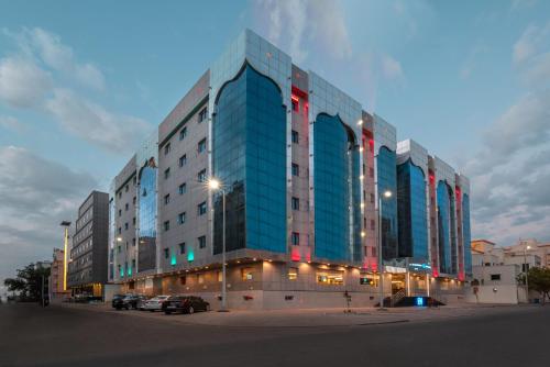 a large glass building with cars parked in front of it at Le Beaurivage Hotel in Jeddah