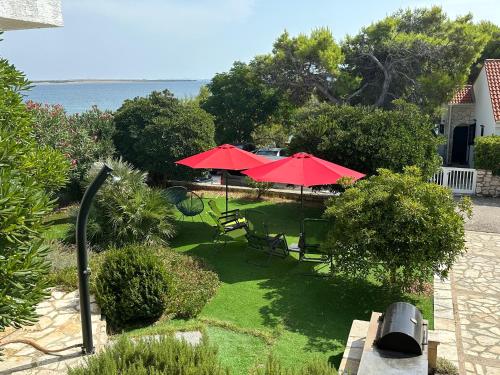 a patio with two red umbrellas and chairs at Villa Eugenia in Košljun