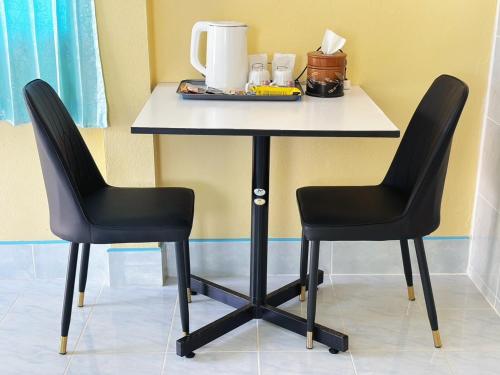 a table with two black chairs sitting next to a table at Thungwua laen resort in Chumphon