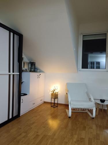 a living room with a white chair and a window at Sky room 12 in Mladenovac