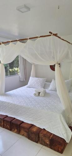 a bedroom with a canopy bed with white sheets at Sunrise Paradise in Cayru