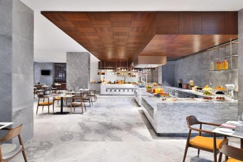 a restaurant with tables and chairs and a kitchen at Le Meridien Hyderabad in Hyderabad