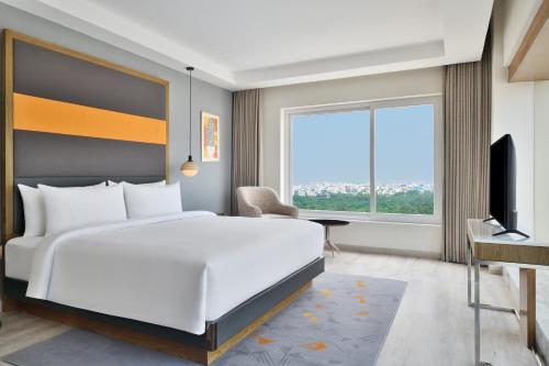 a bedroom with a large white bed and a window at Le Meridien Hyderabad in Hyderabad