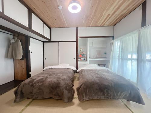 a bedroom with two beds and a large window at 夕日と海の貸切宿 海しずく in Kami Amakusa