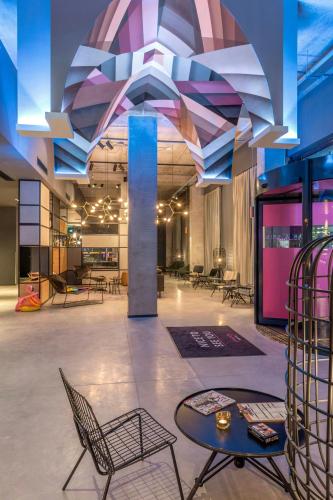 a lobby with chairs and a table in a building at Moxy Milan Linate Airport in Segrate