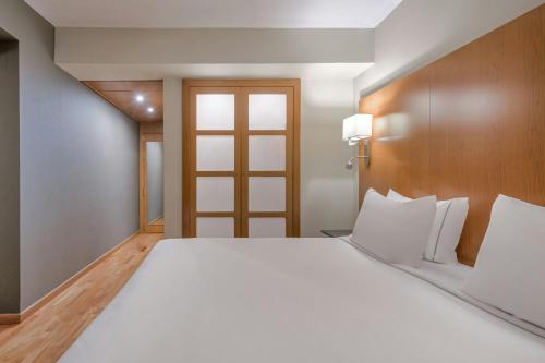 a large white bed in a room with a door at AC Hotel Sevilla Fórum by Marriott in Seville