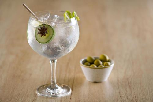 a drink with a kiwi in it next to a bowl of olives at AC Hotel Sevilla Fórum by Marriott in Seville