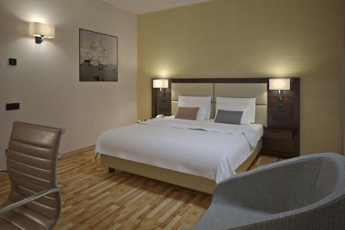 a bedroom with a large white bed and a chair at AC Hotel by Marriott Milan Sesto in Sesto San Giovanni