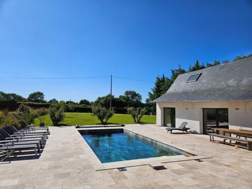 - une piscine dans un patio avec des chaises et un bâtiment dans l'établissement La Parenthèse Normande, à Saint-Cyr-du-Ronceray
