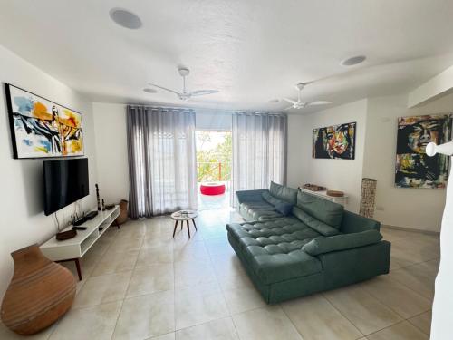 a living room with a green couch and a television at Sunrise Paradise in Cayru