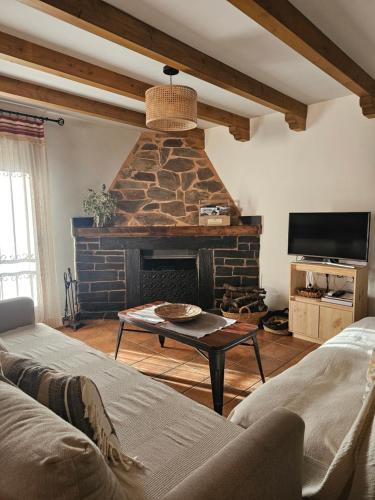 a living room with a stone fireplace and a couch at El Descanso de Las Hurdes in Sauceda