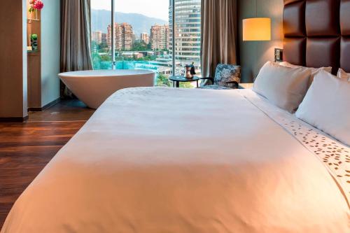 a large white bed in a hotel room with a tub at Renaissance Santiago by Marriott in Santiago