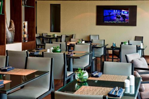 a restaurant with tables and chairs and a television on the wall at Renaissance Santiago by Marriott in Santiago