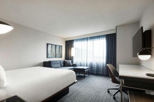 a hotel room with a bed and a desk at Courtyard by Marriott Montreal Airport in Dorval