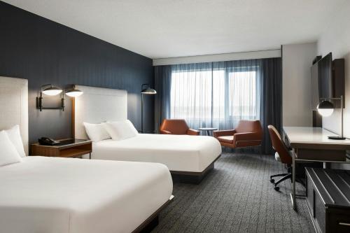 a hotel room with two beds and a desk at Courtyard by Marriott Montreal Airport in Dorval